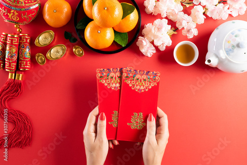 中国新年的节日装饰。女人手里拿着红包、桔子和金锭