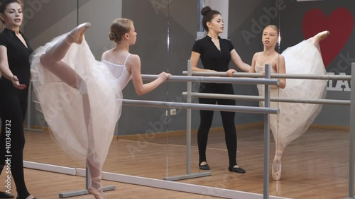 芭蕾舞老师教年轻的芭蕾舞女演员在镜子前跳舞。