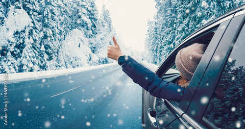 快乐的女人在车里用手指在雪地背景上做手势。
